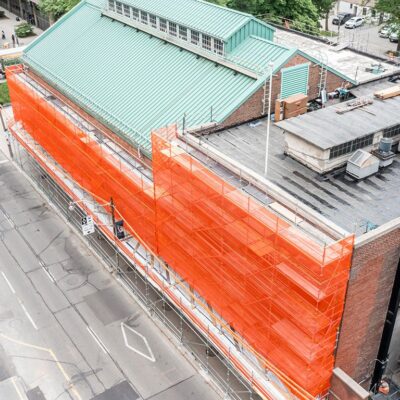 Orange Scafnet covering scaffolding on a large building.
